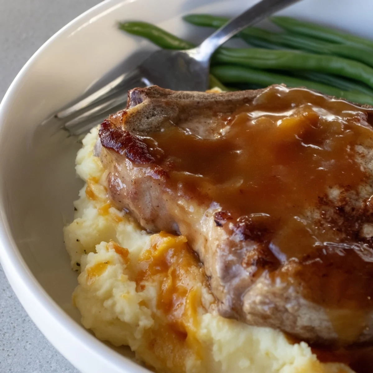 Comforting pork chops & cheddar mash bowl, drizzled with rich gravy for flavor.