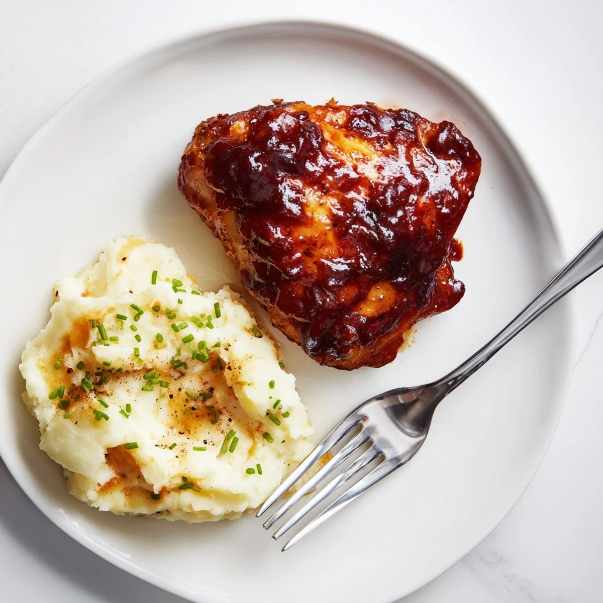 Succulent honey BBQ chicken thighs with creamy garlic mashed potatoes, perfect for dinner.  