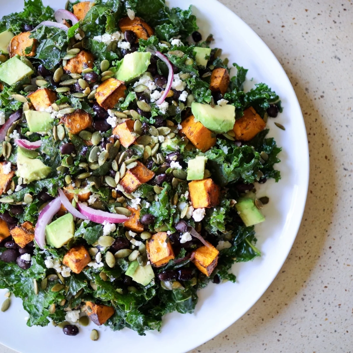 A healthy and delicious Massaged Kale Salad presented with roasted sweet potato and a lime dressing.