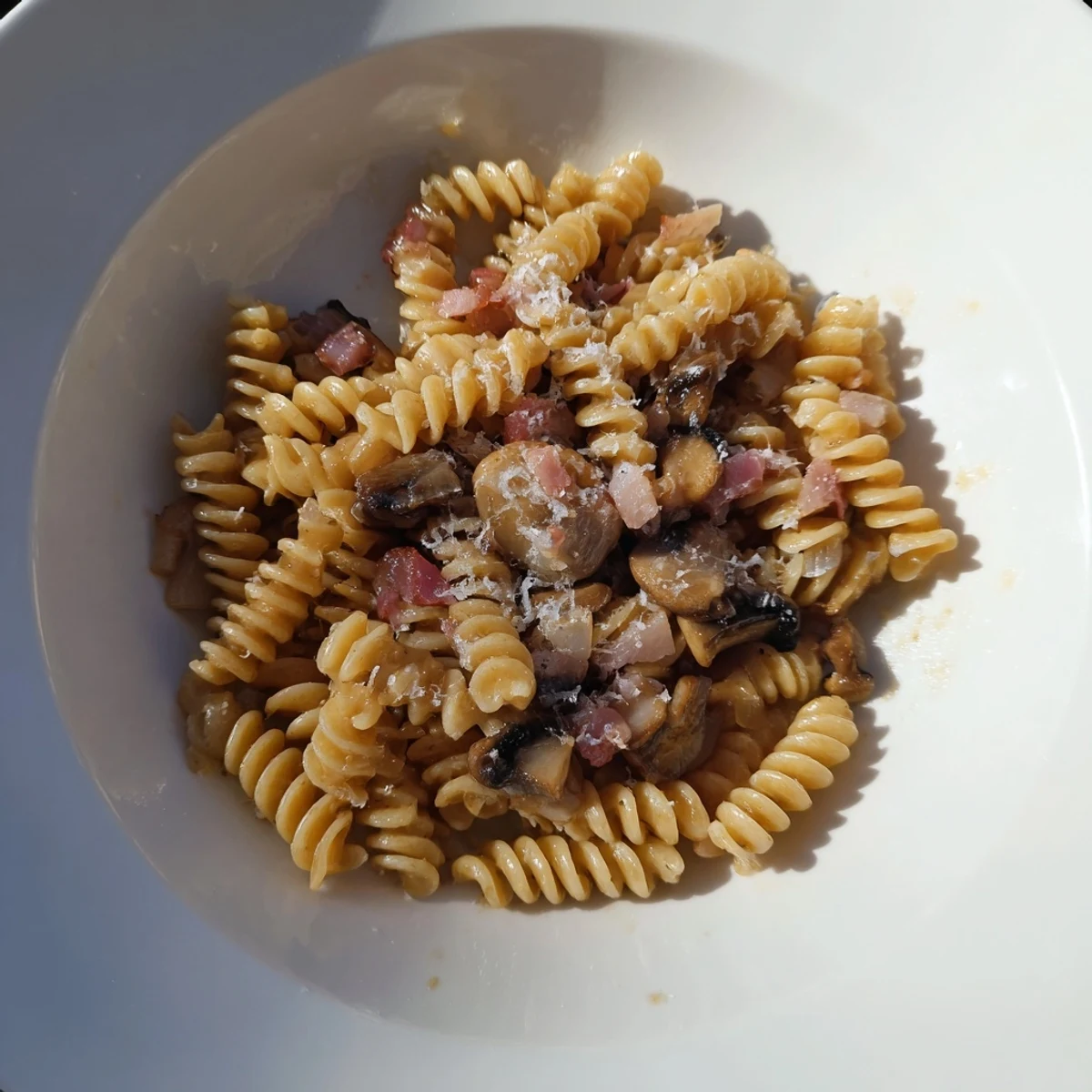 Golden-brown fusilli with bacon, onions, and mushrooms: a comforting Italian-inspired pasta dish.