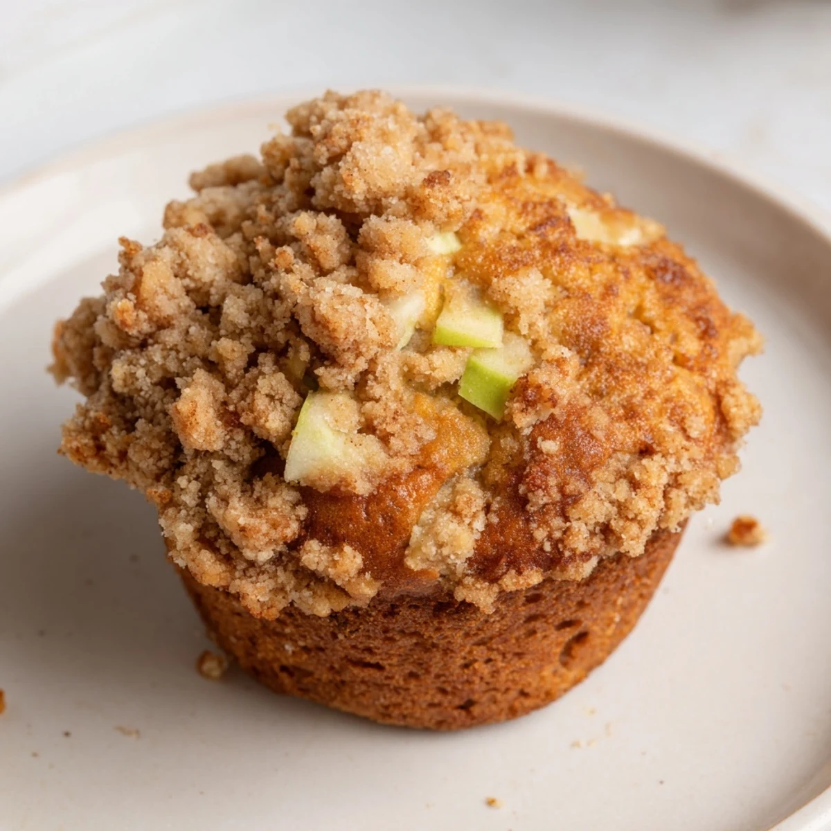 Golden-brown tasty apple muffins with a delightful crumb topping, perfect for an afternoon snack.