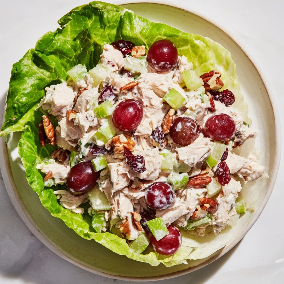 Festive Chicken Salad Cups, filled with grapes and pecans, nestled in crisp lettuce—a delicious appetizer.