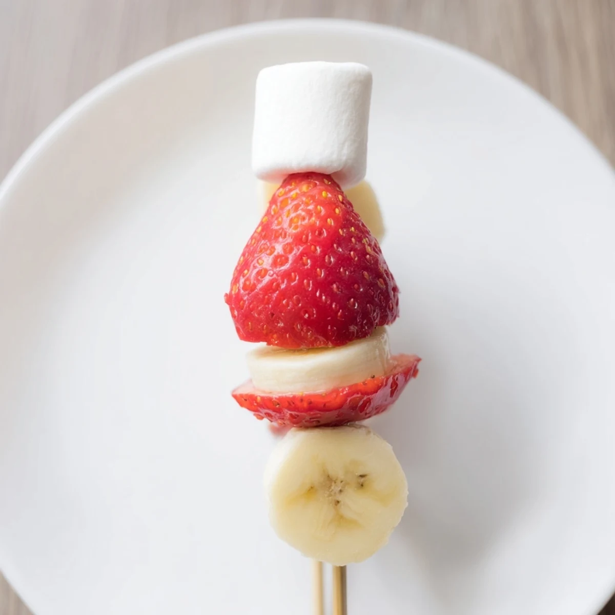 Festive Strawberry Banana Santa Sticks, ready to eat, with red berries, bananas, and a sweet marshmallow pom-pom.