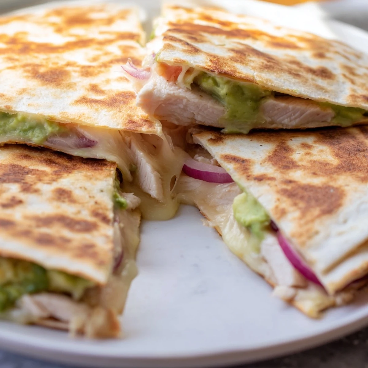 Golden brown Chicken Avocado Quesadilla wedges stuffed with grilled chicken and gooey melted cheese.
