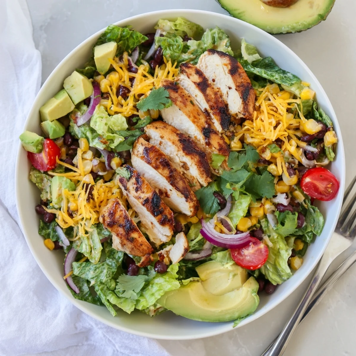Honey lime chicken taco salad with fresh avocado, shredded cheese, and tortilla strips on a bed of crisp romaine.  