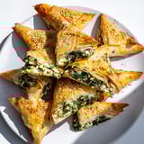 Golden, crispy Mini Spanakopita Triangle Cluster appetizer with inviting, flaky phyllo dough around a cheesy filling.