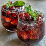 A refreshing non-alcoholic sangria featuring white grape and citrus, garnished with strawberries and mint leaves.
