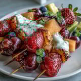 Vibrant fruit skewers arranged in rainbow order, featuring fresh strawberries, melon, and blueberries, paired with a luscious honey-vanilla yogurt dip.