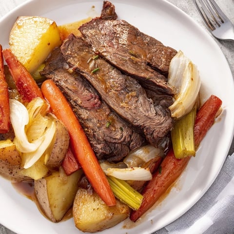 Tender Sunday pot roast surrounded by savory roasted veggies on a rustic table.  