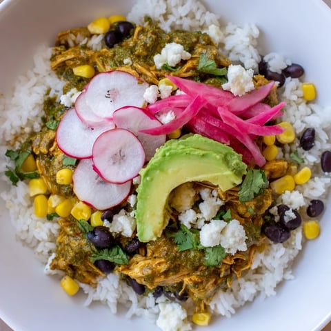A colorful Green Enchiladas Rice Bowl overflowing with chicken, fresh toppings, and zesty sauce.
