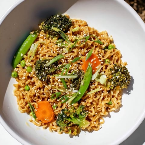 Steaming ramen noodle stir-fry remix, a colorful meal bursting with vegetables and a savory sauce.