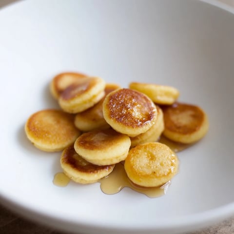 Golden, miniature pancake cereal, drizzled with sweet maple syrup, perfect for a fun breakfast.