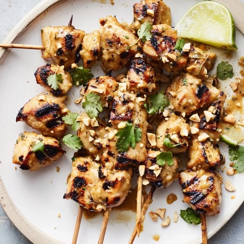Juicy Spicy Peanut Satay Chicken Skewers, grilled with a caramelized glaze and sprinkled with peanuts.