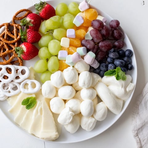 Vibrant Cloud & Rainbow Grazing Board with colorful fruits, cheeses, and sweet candies for a festive party.