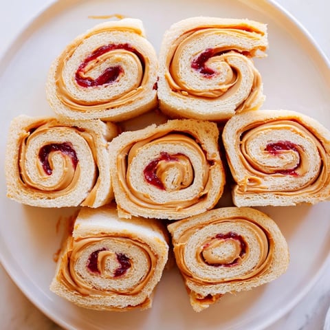 Freshly cut Simple Sandwich: Quartered PB&J Pinwheel Rolls with vibrant peanut butter and jelly spirals.