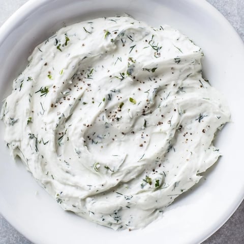 Creamy Greek Yogurt Herb Dip, speckled with fresh herbs, is ready to be scooped with crisp veggies.