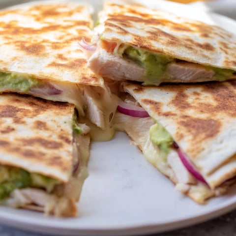Golden brown Chicken Avocado Quesadilla wedges stuffed with grilled chicken and gooey melted cheese.