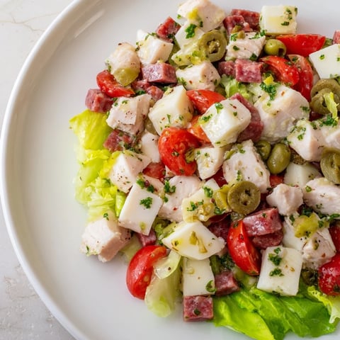 A close-up of Italian Deli Chopped Chicken Salad with vibrant romaine, diced salami, and provolone cheese tossed in a herb dressing.