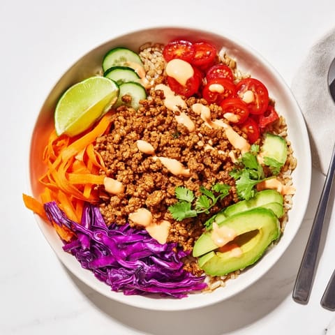 Hearty plant-based meat bowl with avocado, cilantro, and zesty lime wedges.  