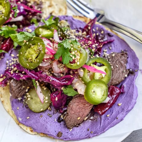 Vibrant Fusion Tacos featuring juicy marinated beef, crispy veggies, and creamy ube sauce.  
