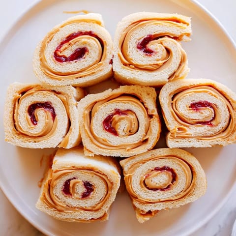 Freshly cut Simple Sandwich: Quartered PB&J Pinwheel Rolls with vibrant peanut butter and jelly spirals.