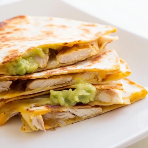 A crispy flour tortilla reveals creamy avocado mash, sliced chicken, and red onion inside.