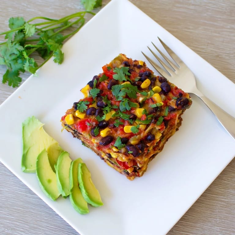Close-up of a fresh-baked Quick Black Bean and Corn Tortilla Casserole, served with fresh cilantro and avocado.