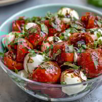 Mason Jar Caprese Salad with layers of cherry tomatoes, mozzarella, and basil, drizzled with balsamic dressing.