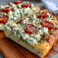 Viral Cottage Cheese Flatbread topped with bright pesto, tomatoes, and herbs.